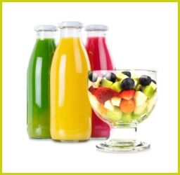 Drei bunte Fruchtsäfte in Glasflaschen mit frischem Obstsalat in Dessertschale auf weißem Hintergrund